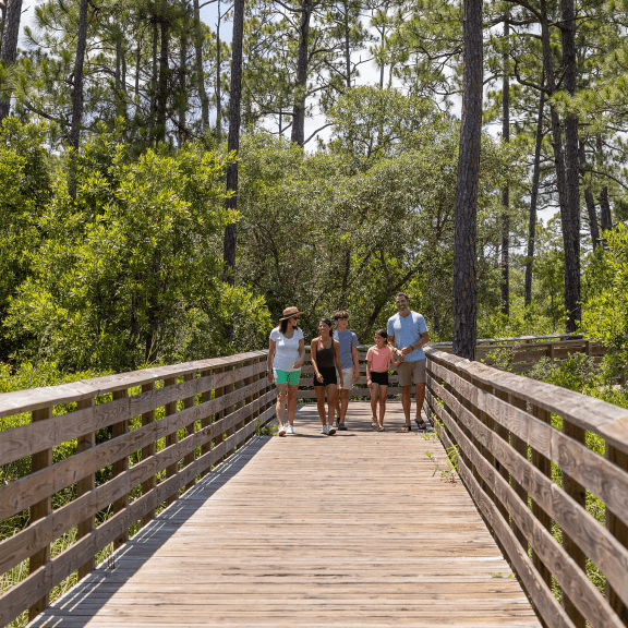 Family walking on a boardwalk along the Hugh S. Branyon Backcountry Trail in Gulf State Park